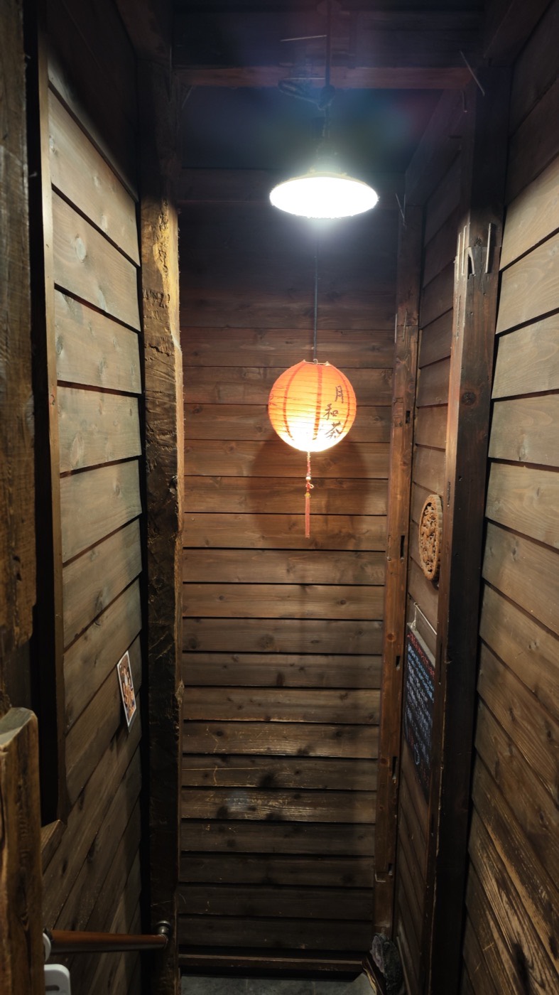 Narrow wooden staircase to the second floor with a red paper lantern reading Yue He Cha