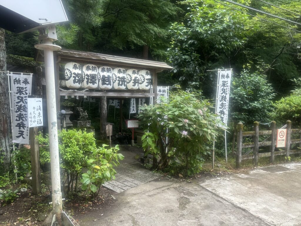 The entrance to Zeniarai Benten shrine in Kamakura: a stone torii and rock-cut tunnel through the cliff face, with the shrine name carved on a stone marker