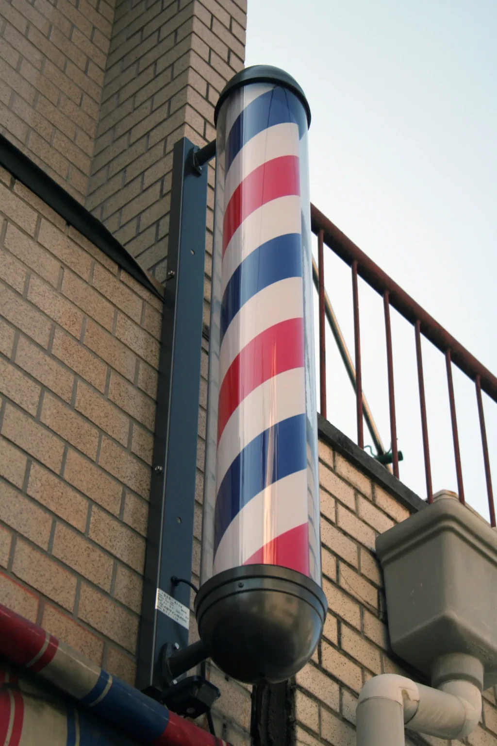 A red, white and blue barber pole on a brick wall in Japan