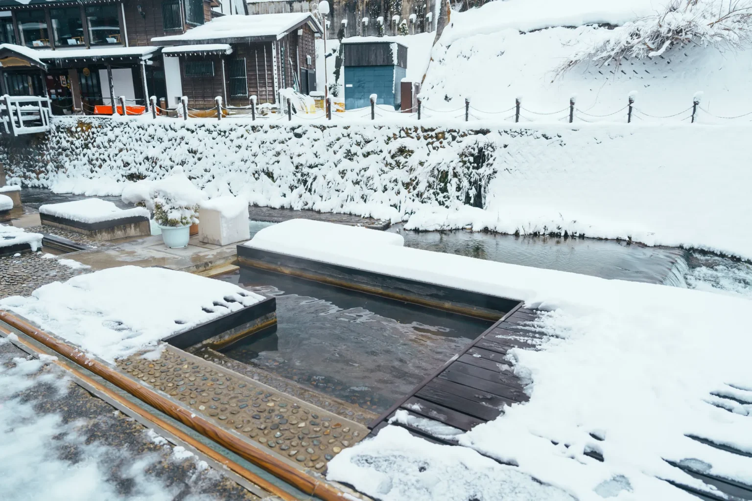 The Warashiyu foot bath beside the river in Ginzan Onsen, surrounded by snow