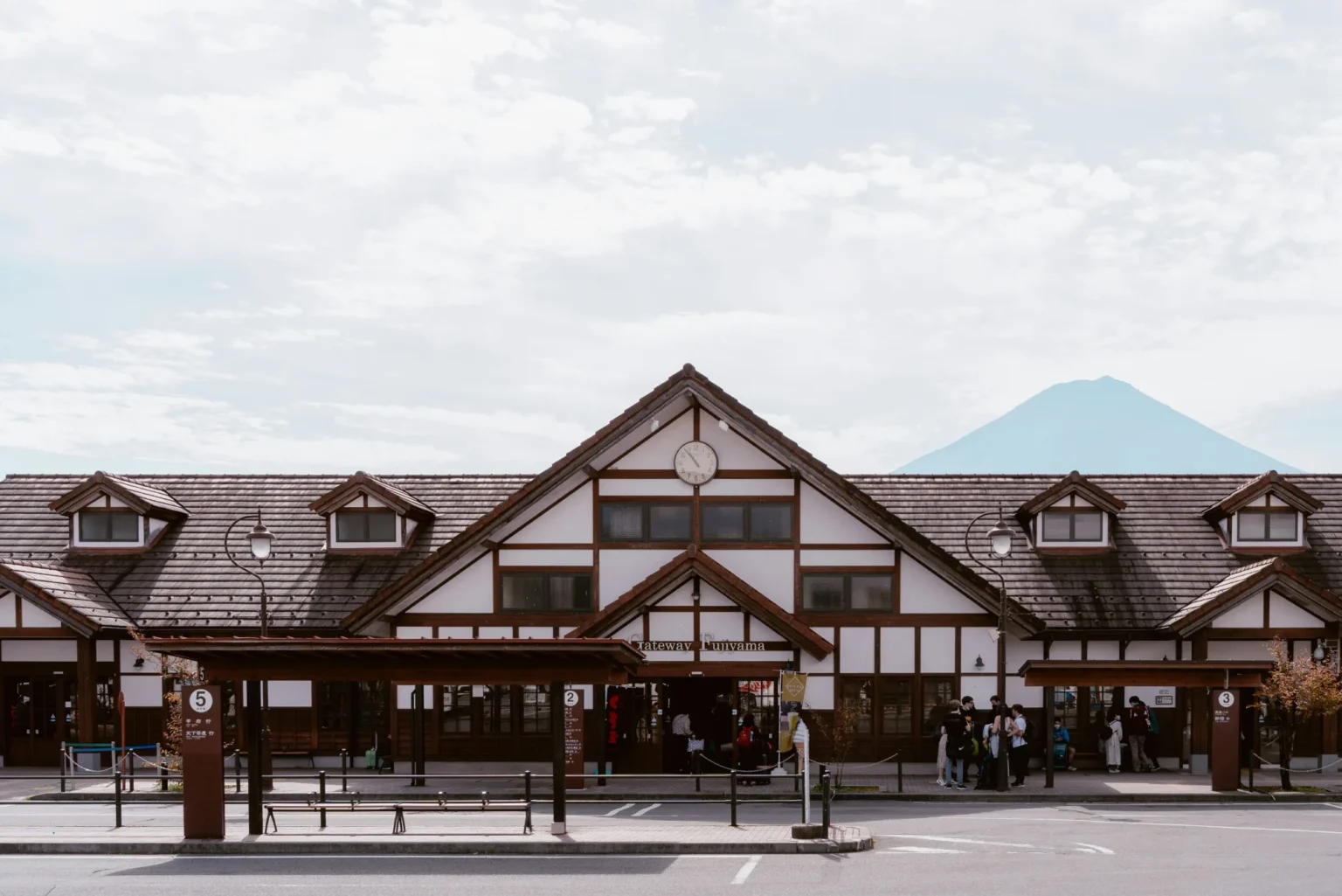 The timber-framed, chalet-style Kawaguchiko Station building with a clock in its central gable and Mt Fuji behind