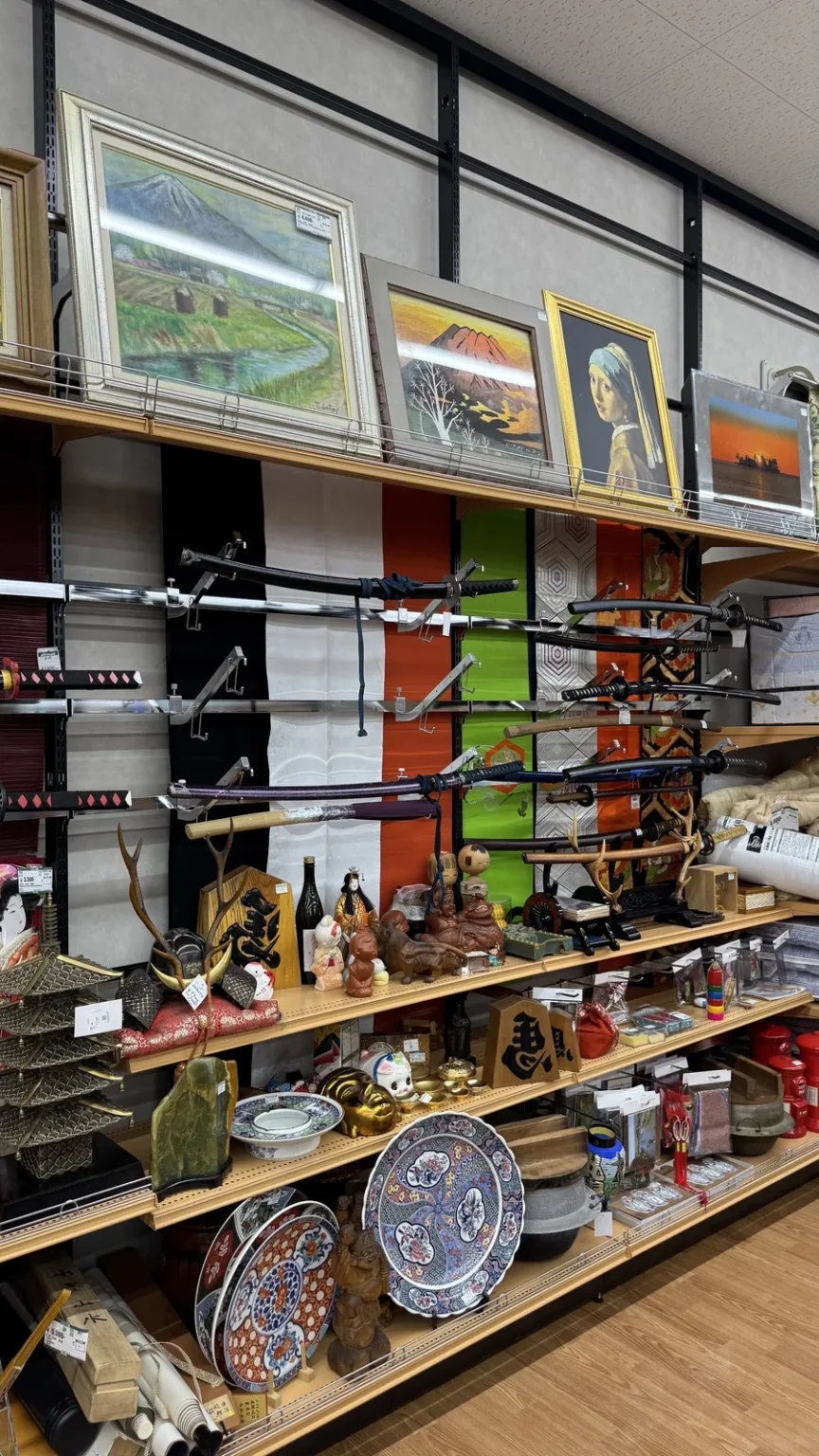 Shelves with framed paintings at the top, swords on stands in the middle and ceramic plates below