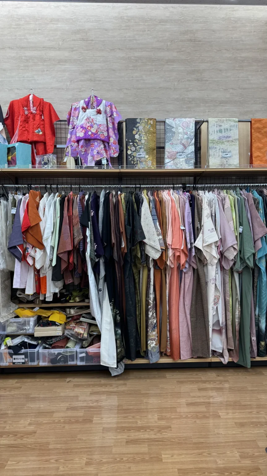 Kimono in red and purple displayed above a rack of used kimono and haori jackets