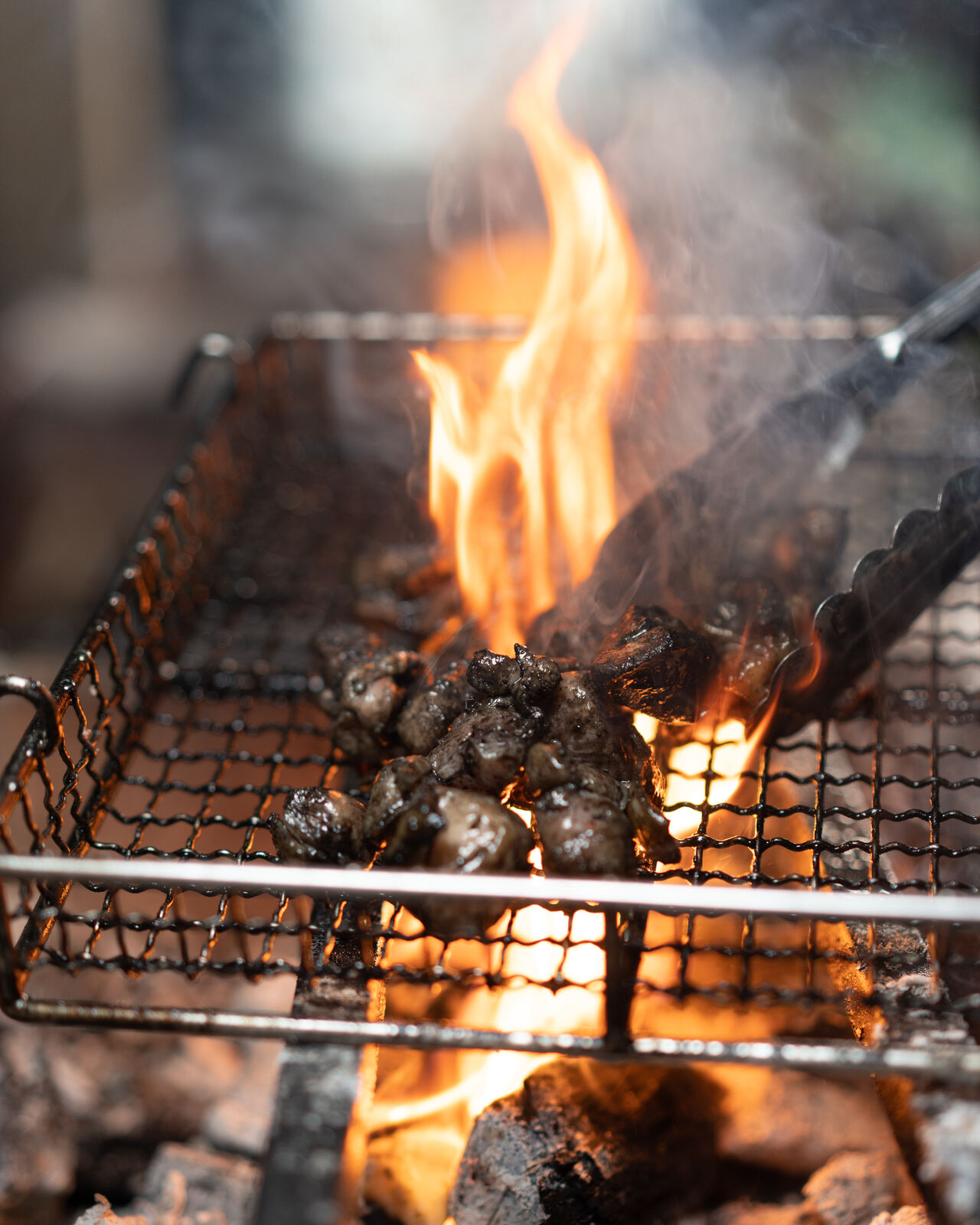 Tall flames rising through a wire grill full of chicken