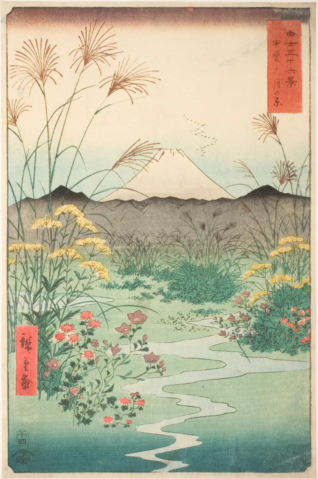 Vertical woodblock print: tall pampas grass, yellow and red autumn flowers and a winding pale stream fill the foreground of a wide plain. Beyond a line of grey hills, a white Mount Fuji rises under a pale sky with a few flying geese.