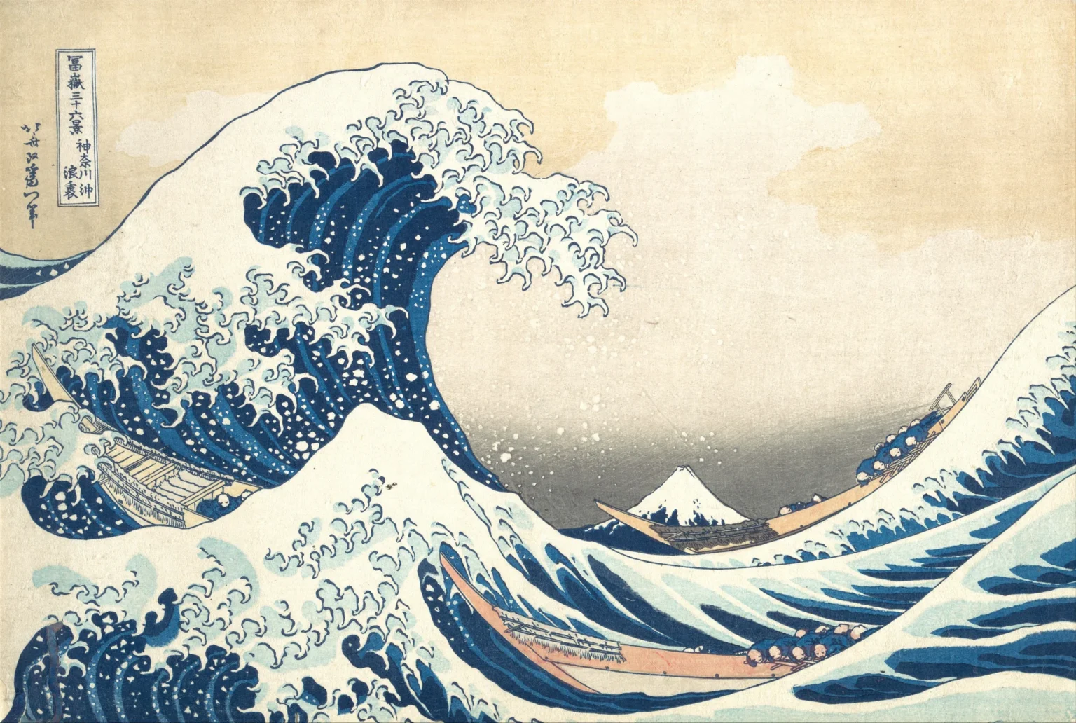 Woodblock print of a huge dark-blue wave curling over three long, narrow boats full of rowers, its white crest breaking into claw-like spray. Far away in the trough of the waves sits a small snow-capped Mount Fuji under a pale yellow sky.