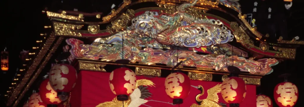 Gilded dragon carvings, red paper lanterns and a curtain embroidered with cranes on a Chichibu Night Festival float at night