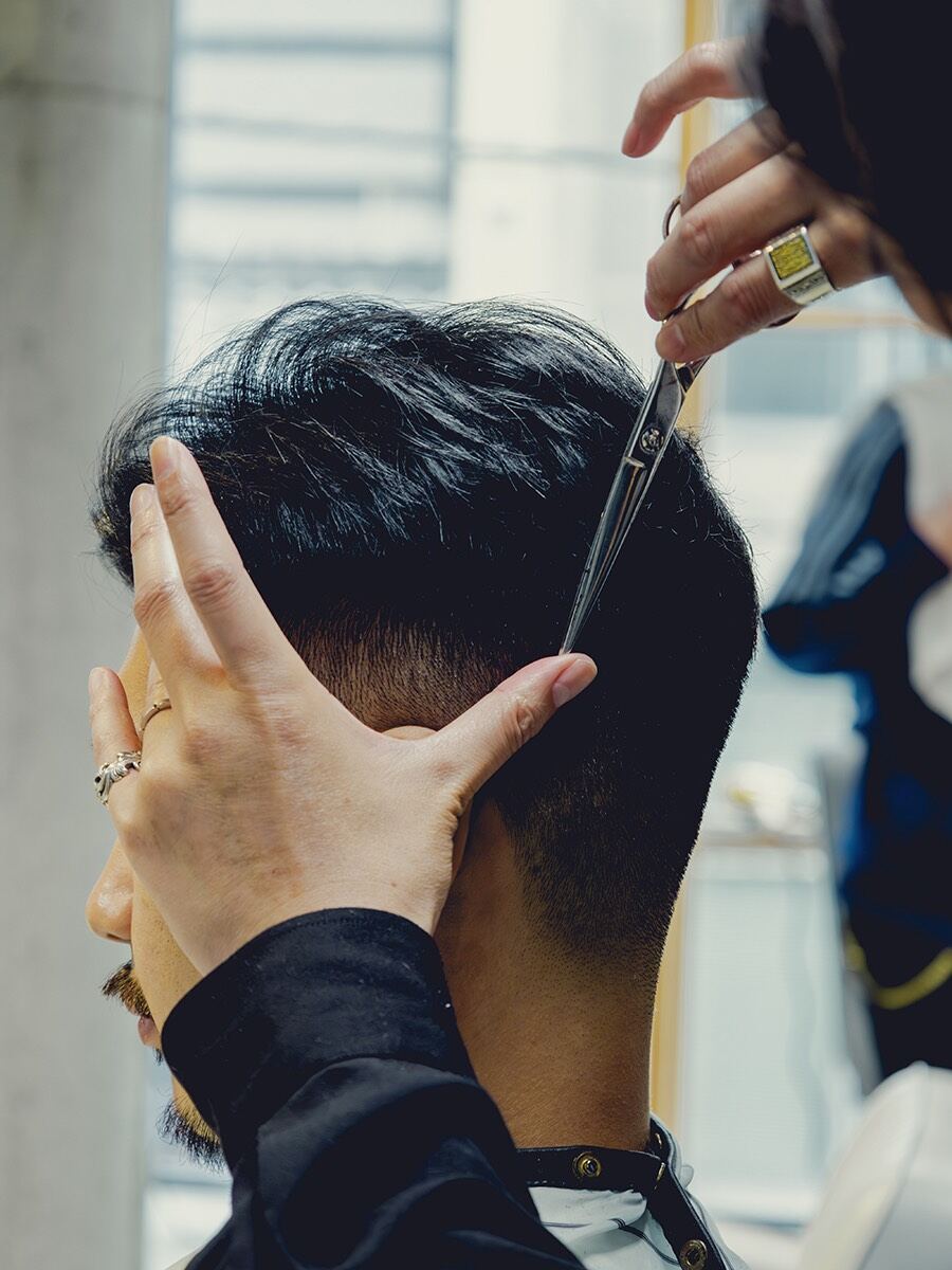 Close-up of a stylist cutting the back of a customer's hair with scissors