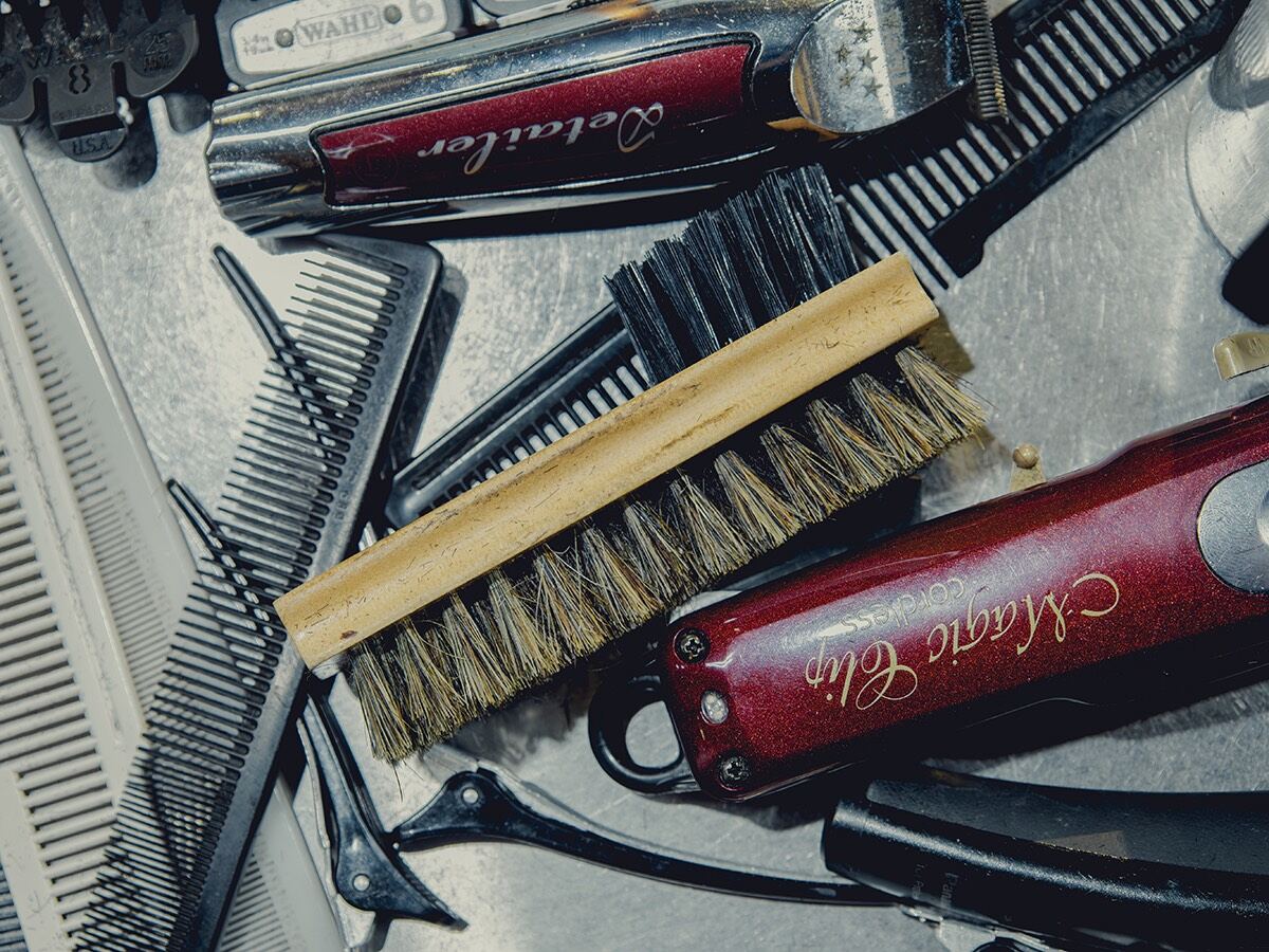 Clippers, combs and a bristle brush laid out on a metal tray