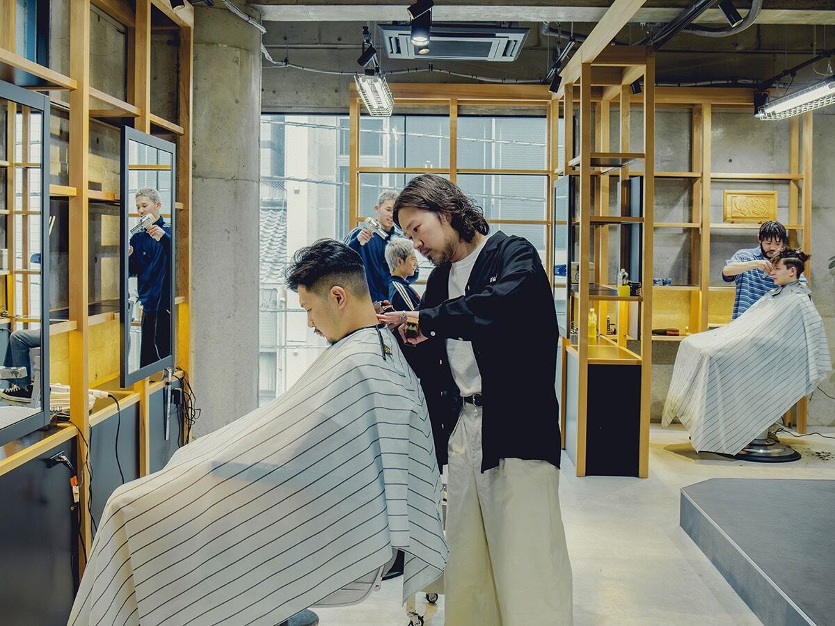 Stylists at work on customers in striped capes in a bright room