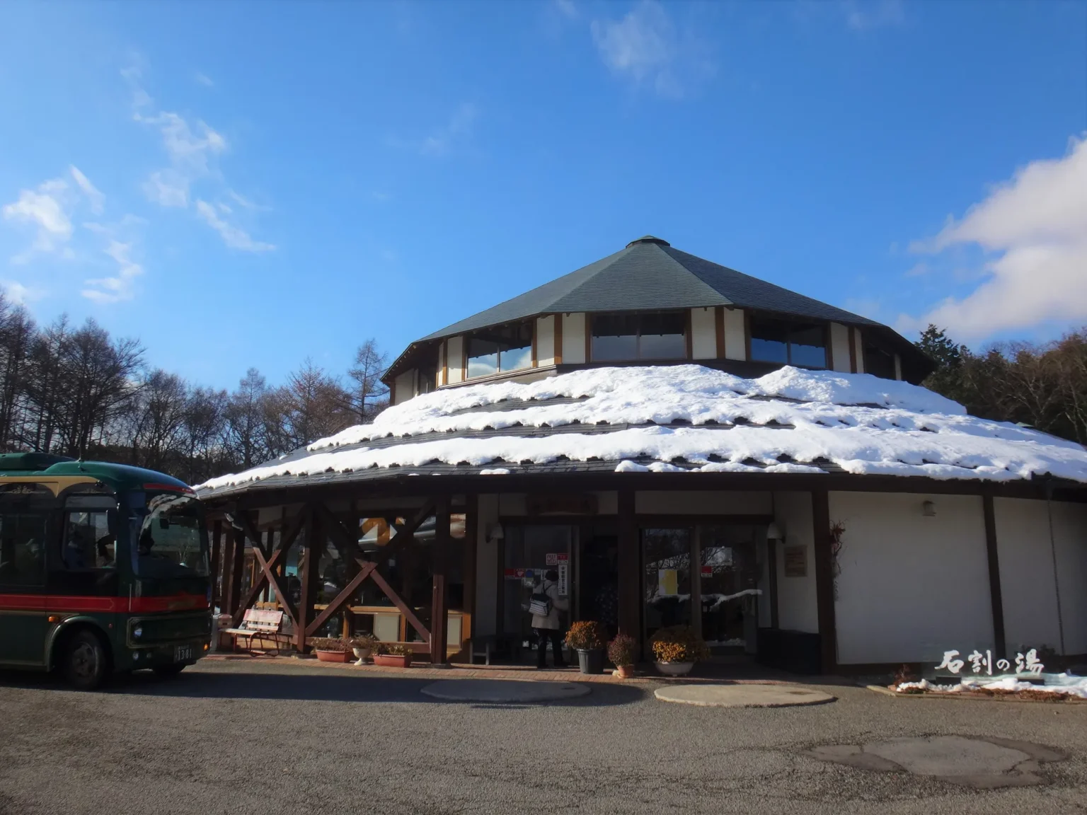 The round Ishiwari no Yu building with snow on its roof and a bus parked outside.