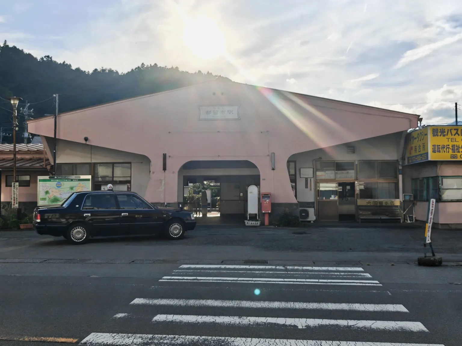 Tsurushi Station’s low pink building with a taxi parked in front.