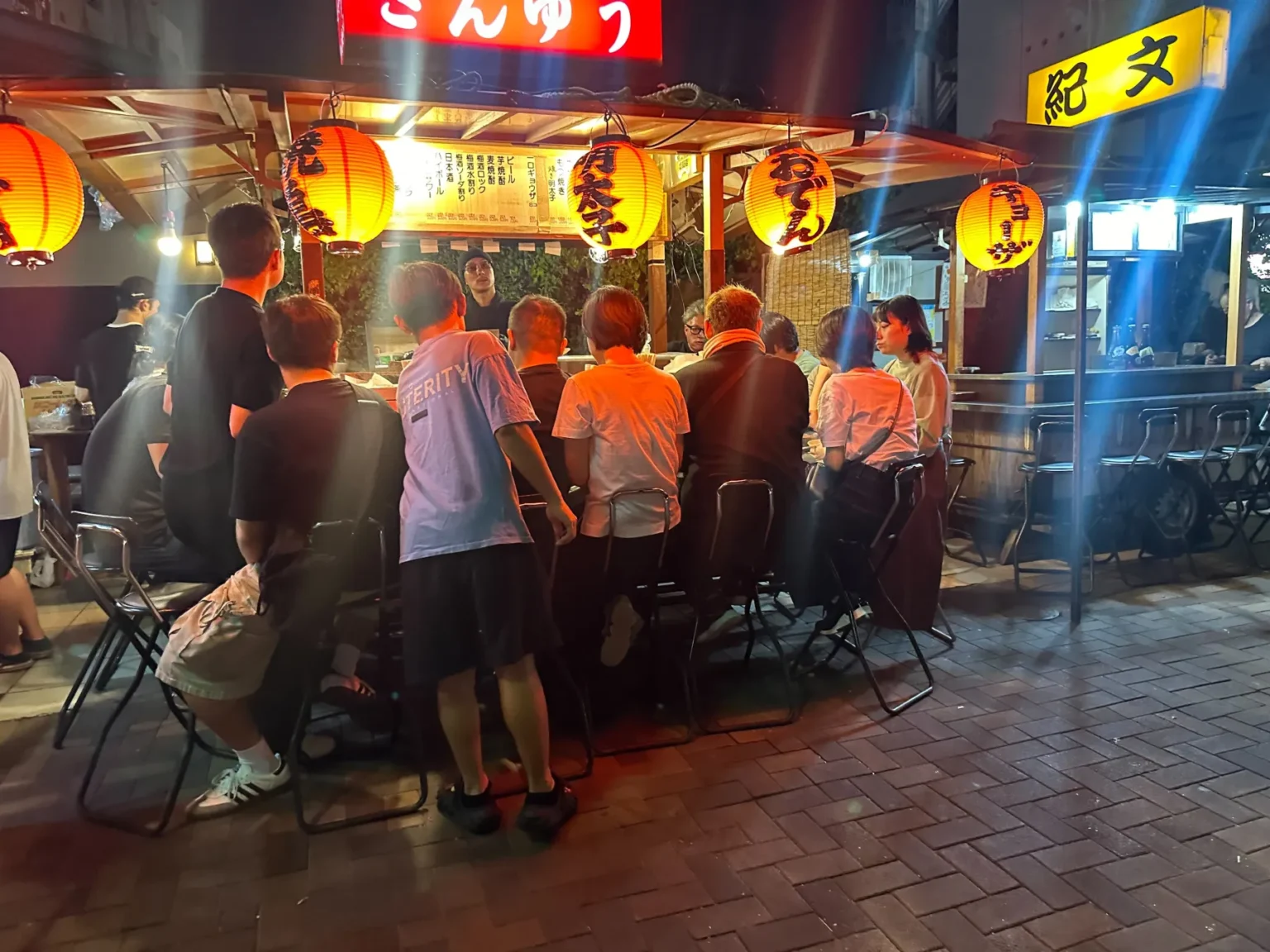 People sitting shoulder to shoulder at the counter of a yatai stall in Nakasu