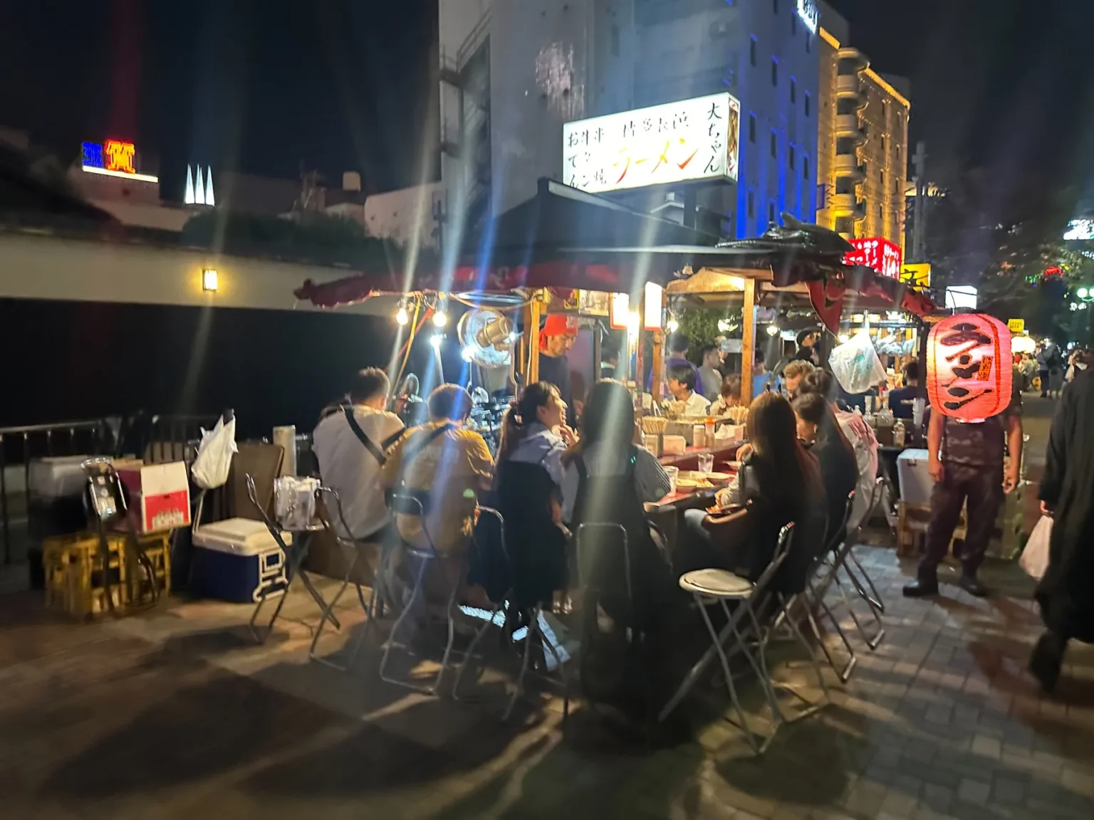 Customers seated at yatai stalls by the river in Nakasu, Fukuoka, at night