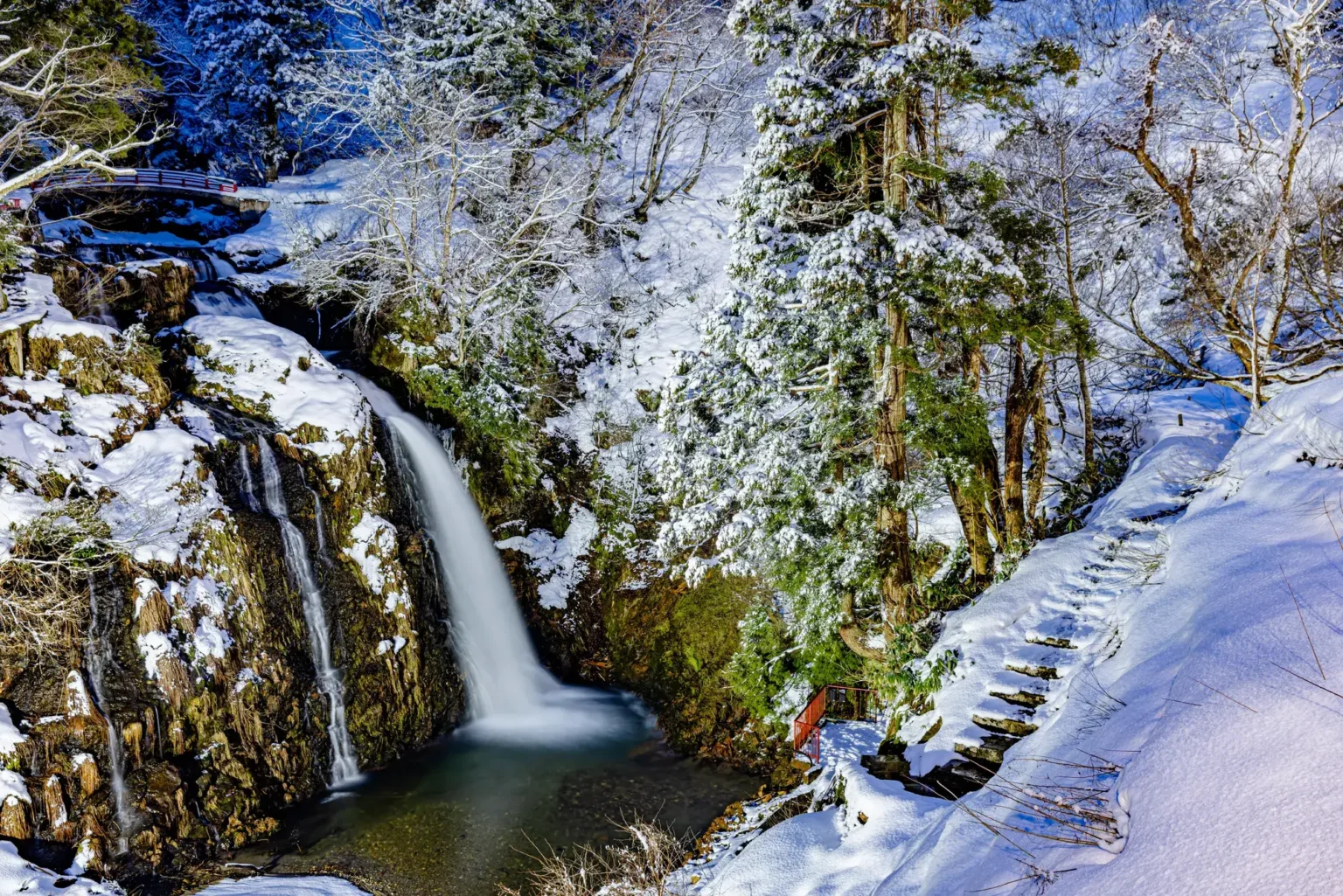 Shirogane Falls at the top of Ginzan Onsen, framed by snow-covered rocks and trees