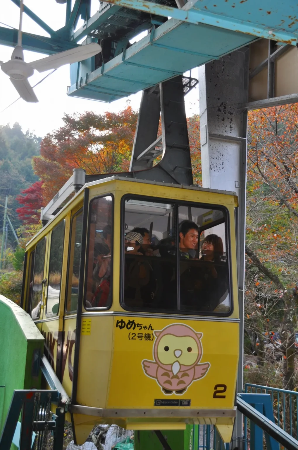 A yellow ropeway gondola with passengers inside at a station platform