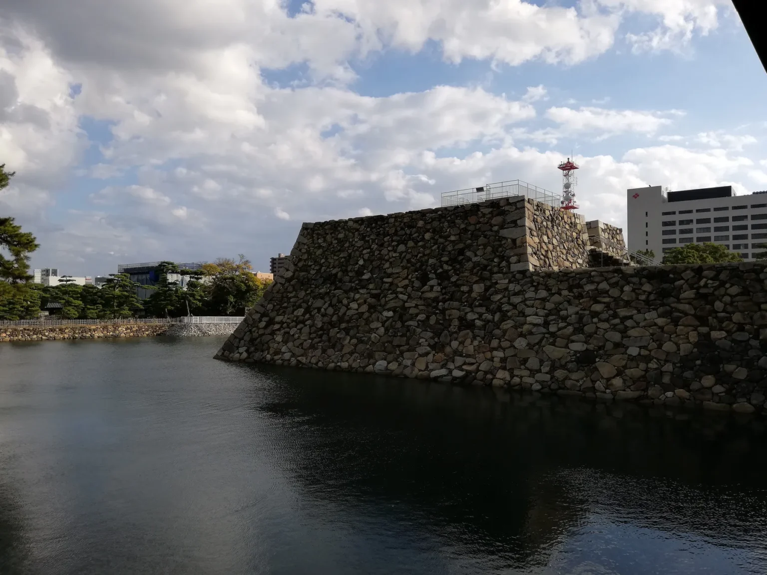 Stone walls of the Takamatsu Castle keep base rising from the inner moat in Tamamo Park