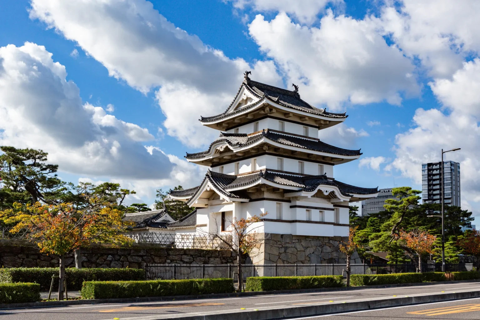 The white Tsukimi Yagura turret of Takamatsu Castle in Tamamo Park under a blue sky