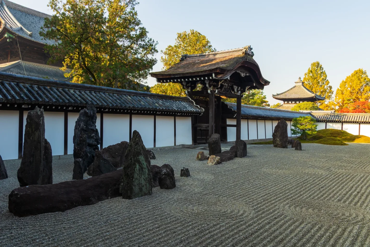 The south garden of the Tofukuji Hojo: raked gravel with tall standing rocks in front of a white wall and a roofed gate