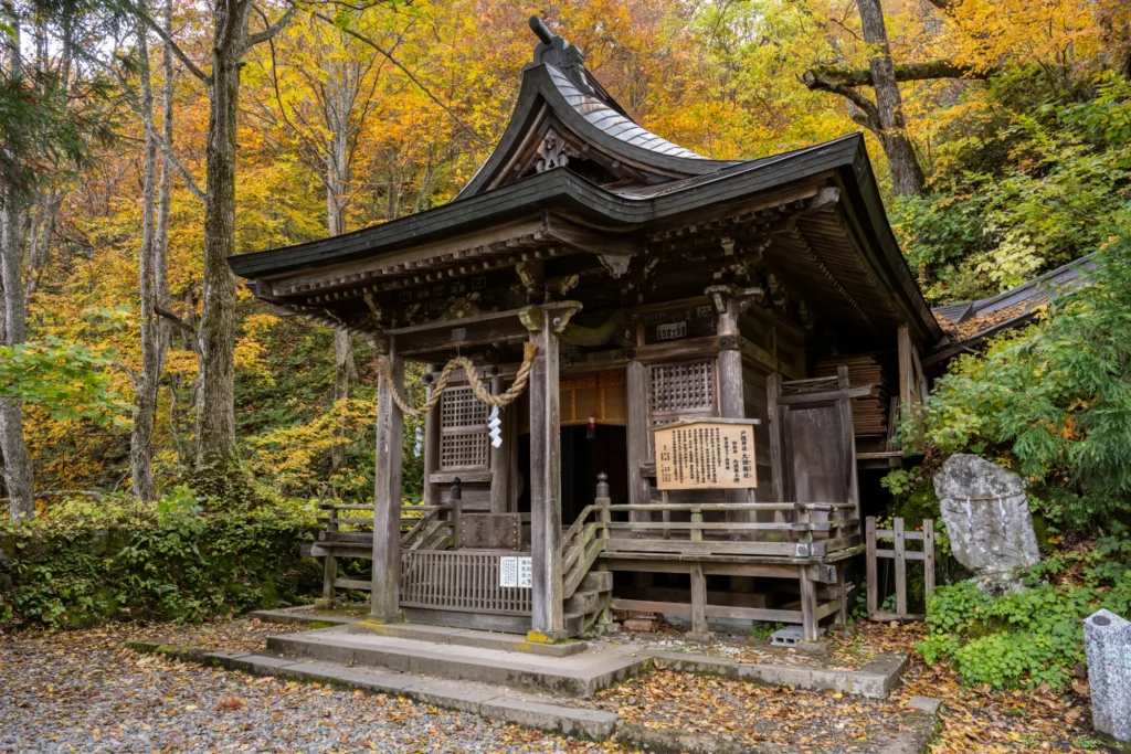 Wooden Kuzuryusha hall with autumn leaves at the top of the Okusha approach, Togakushi Shrine