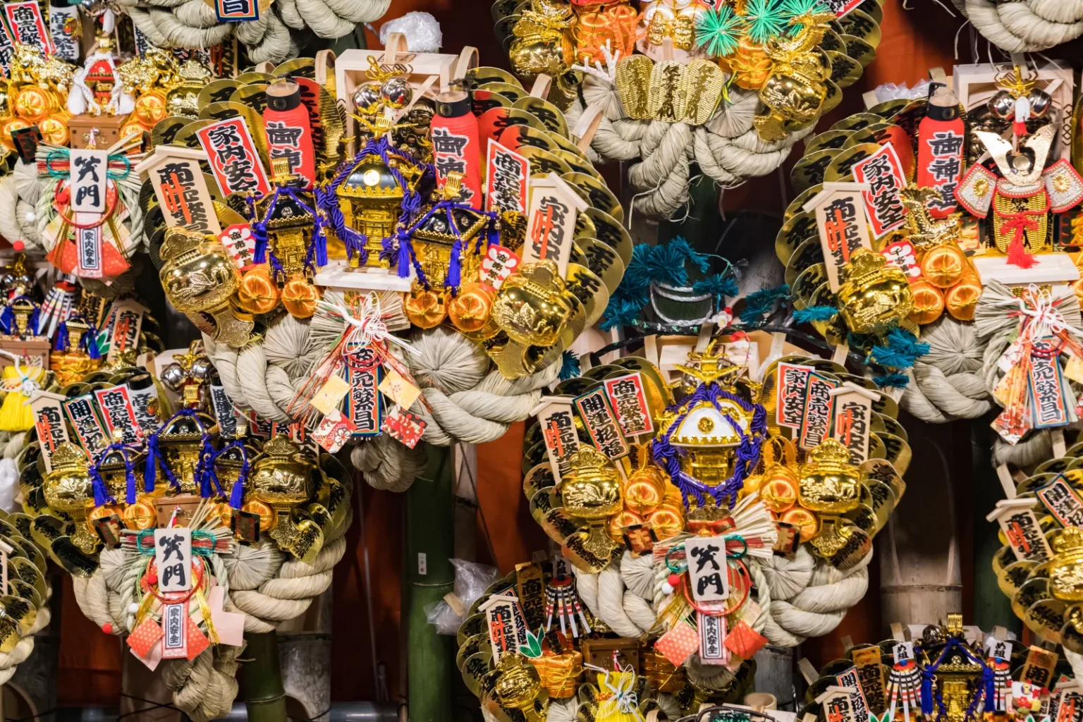 Decorated kumade bamboo rakes covered with gold coins, small shrines, rice-straw ropes and lucky charms on display at a Tori no Ichi stall