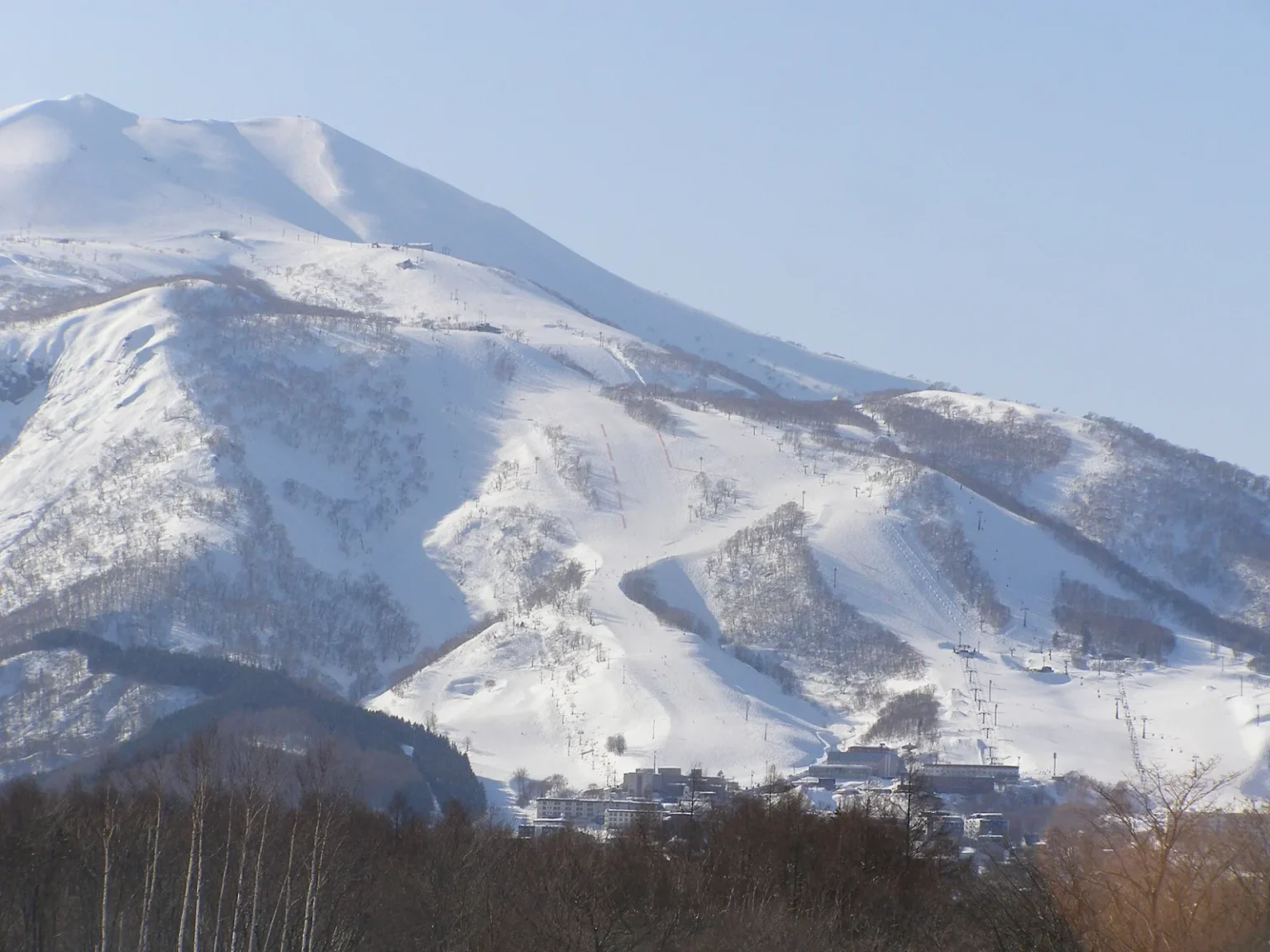 Snow-covered Niseko Annupuri with the ski runs of Grand Hirafu and village buildings at the foot of the slopes, seen from near Route 5 in Kutchan