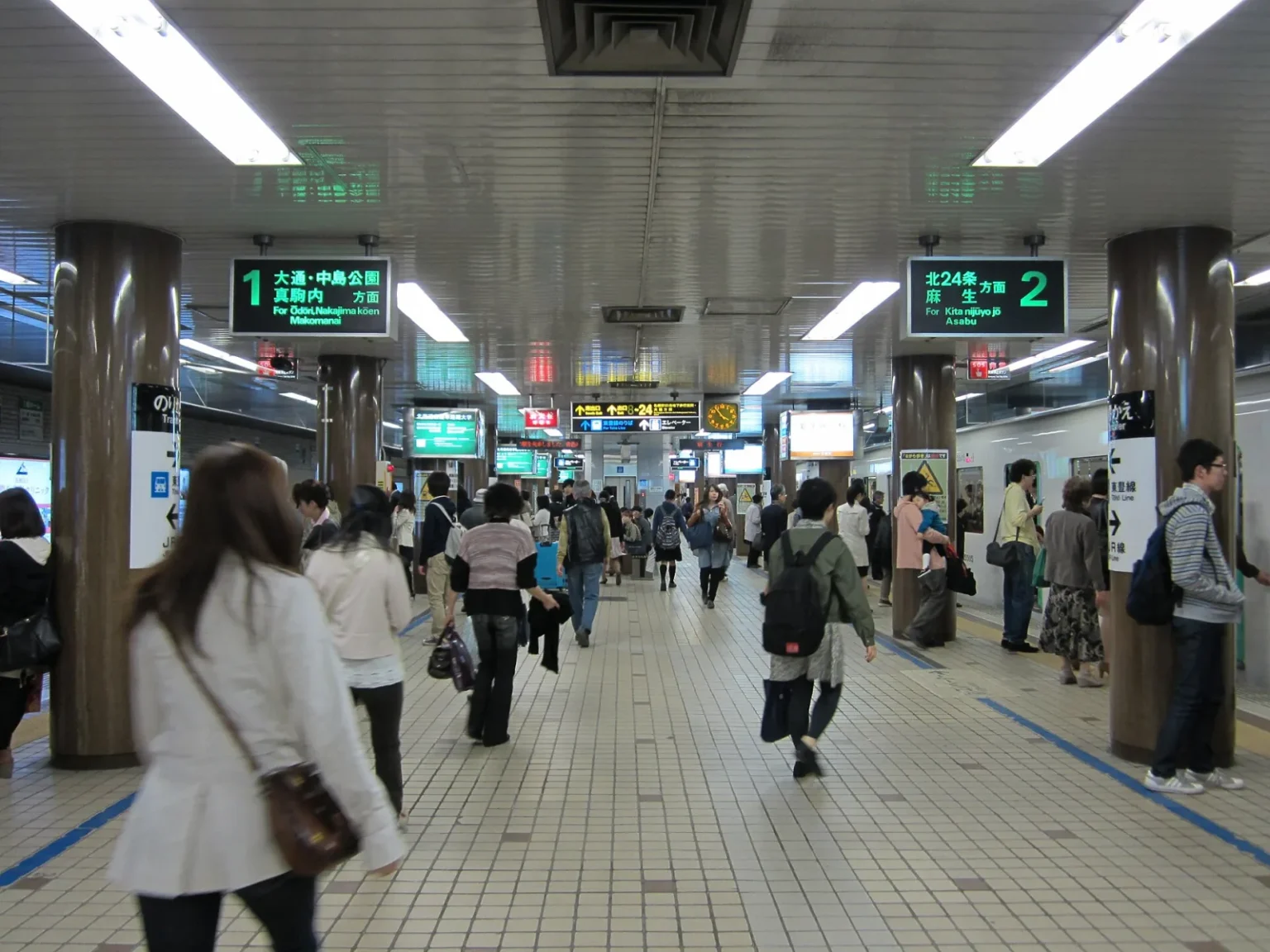 Passengers on the Namboku Line platform at the subway's Sapporo Station, with signs for trains towards Odori, Nakajima-koen and Makomanai